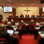 Imagen de la 129ª Asamblea Plenaria CEE en Madrid con el logo de ECO NOTICIA en las pantallas, mostrando a los obispos españoles en reunión.