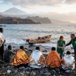 Voluntarios de Cáritas asistiendo a migrantes en las costas de las Islas Canarias con el Teide al fondo.