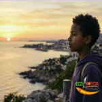 Joven migrante mirando al horizonte, representando la esperanza y los retos de los niños migrantes no acompañados en España.