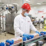 Operarios de producción en Bimbo trabajando en la línea de envasado de pan en la fábrica.