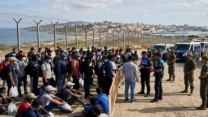 Crisis migratoria en Ceuta con migrantes y fuerzas de seguridad españolas en la frontera
