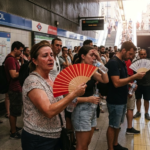 Pasajeros se protegen del calor durante una ola de calor en Madrid
