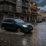 Vehículo circulando por una calle anegada tras lluvias torrenciales