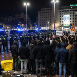 Protesta juvenil y presencia policial en la plaza de Catalunya de Barcelona durante la noche.