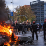 Disturbios durante una protesta en Bilbao con contenedores incendiados y agentes de la Ertzaintza.