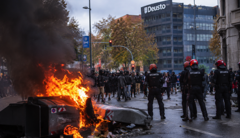 Disturbios durante una protesta en Bilbao con contenedores incendiados y agentes de la Ertzaintza.