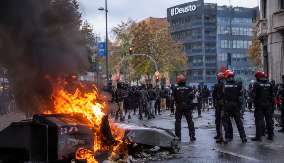 Disturbios durante una protesta en Bilbao con contenedores incendiados y agentes de la Ertzaintza.